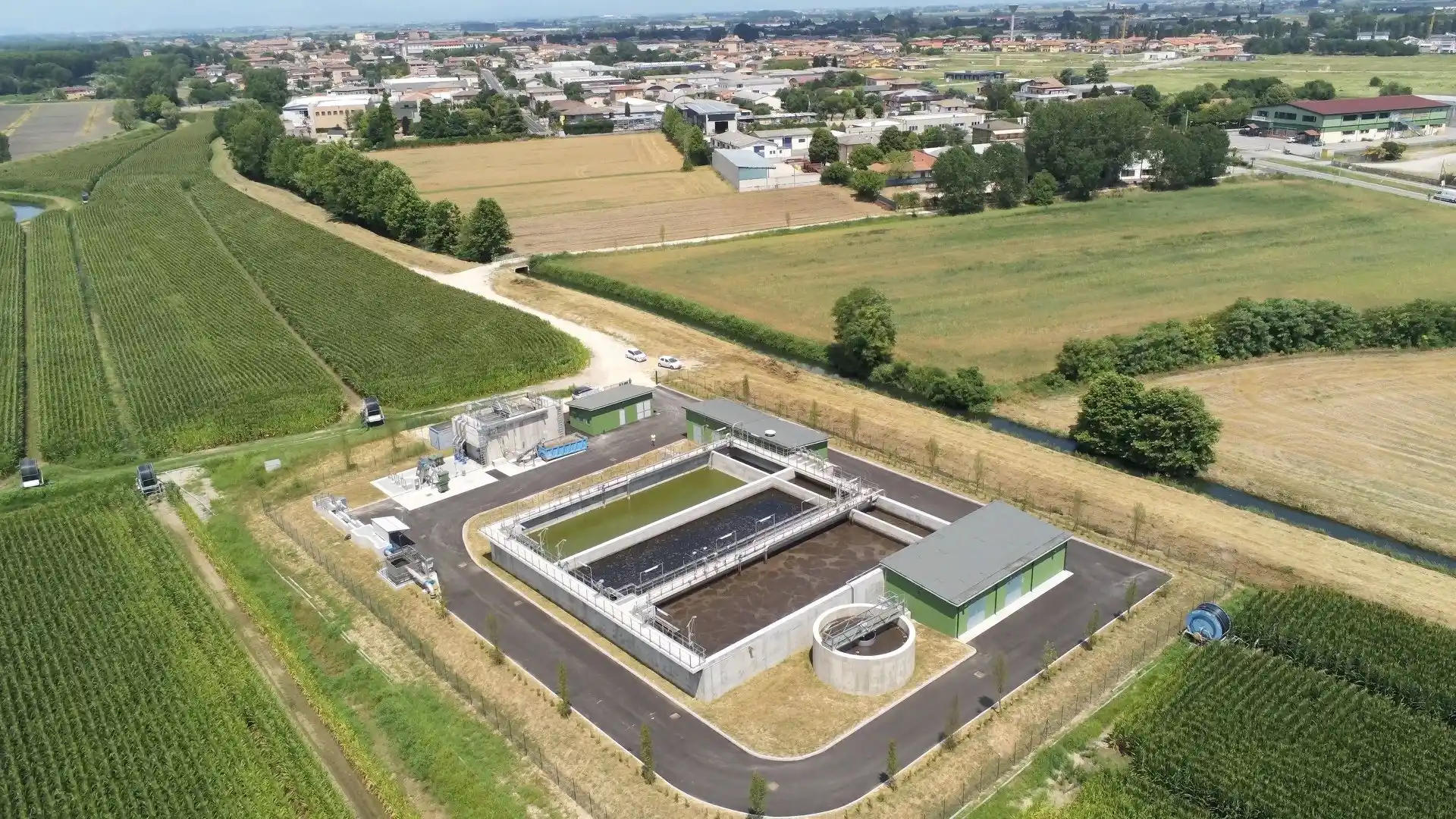Un'immagine aerea di una moderna stazione di trattamento delle acque reflue. Le vasche di sedimentazione e altri impianti di trattamento sono chiaramente visibili, così come un'area di stoccaggio per le apparecchiature. Le aree verdi che circondano l'impianto suggeriscono che si tratta di una struttura rispettoso dell'ambiente.  Le vasche di sedimentazione sono vuote perché sono in fase di pulizia o manutenzione.