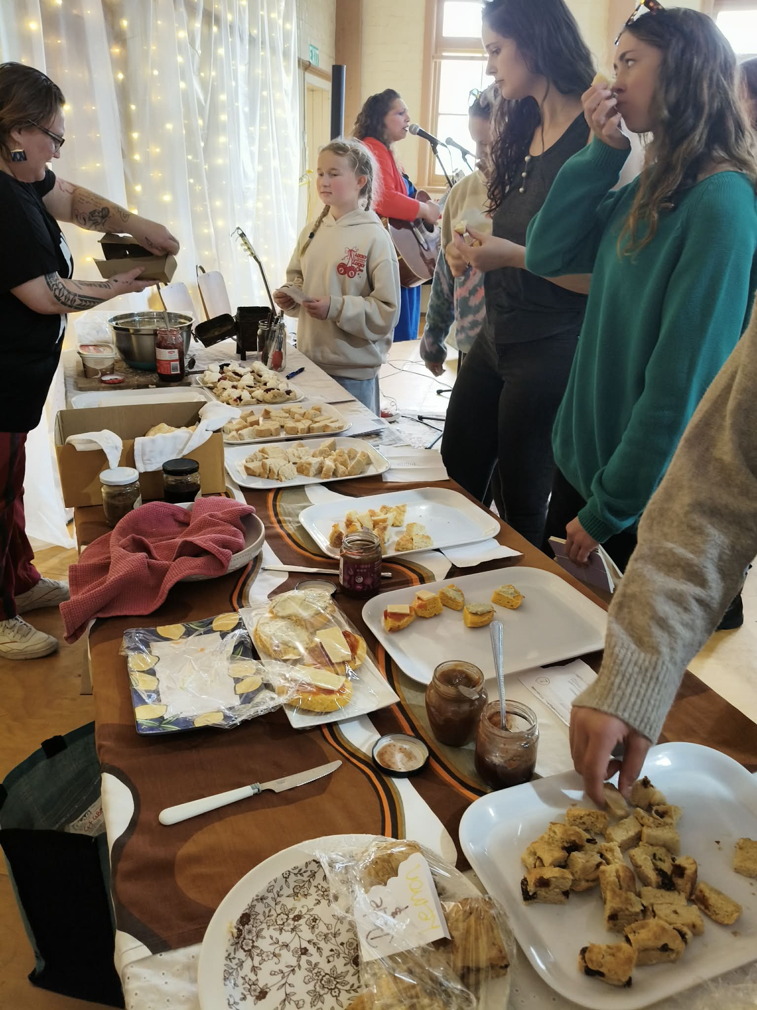 I love this photo as it shows our last entrant, Kate, handing over her scones to Ingrid (who had just been adding jam and cream to her own scone entry). The lovely lady in black, I'd already roped into cutting up the rest of the scone entries and putting them on the plates and she was having her turn at taste testing - thanks heaps for jumping in and helping!! Then of course, there's Iri in the background, entertaining everyone with her beautiful songs!