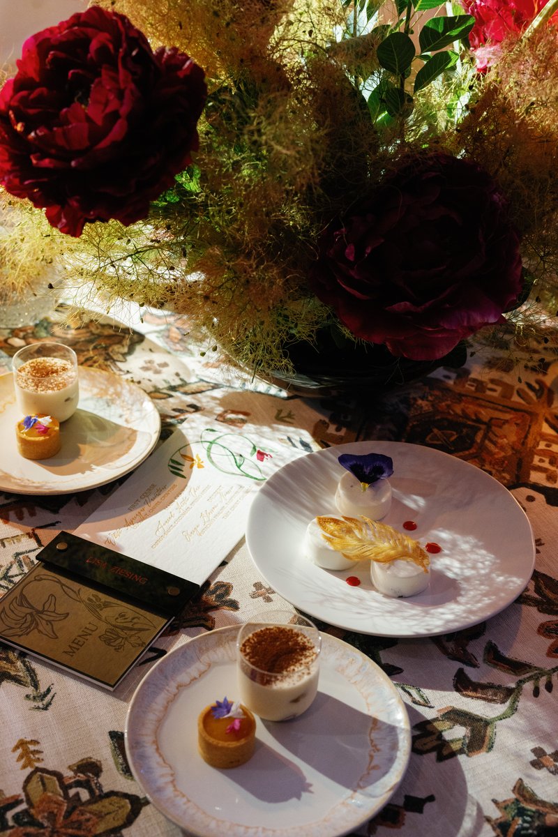 A beautifully arranged table setting showcases an array of elegant desserts and a vibrant floral centerpiece. The scene 