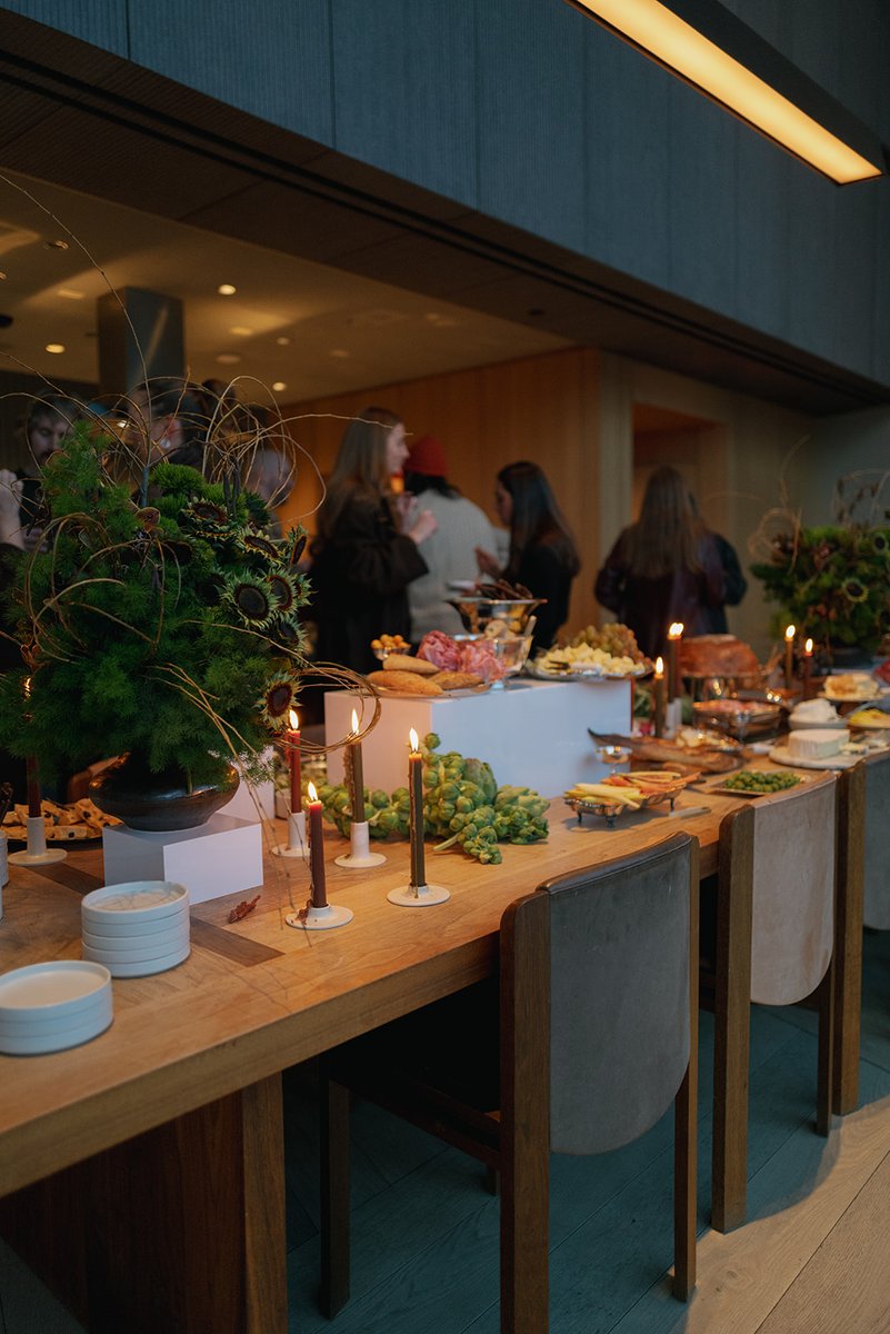 Guests mingle around a beautifully arranged buffet table laden with various appetizers and cheeses. The setting is warm 