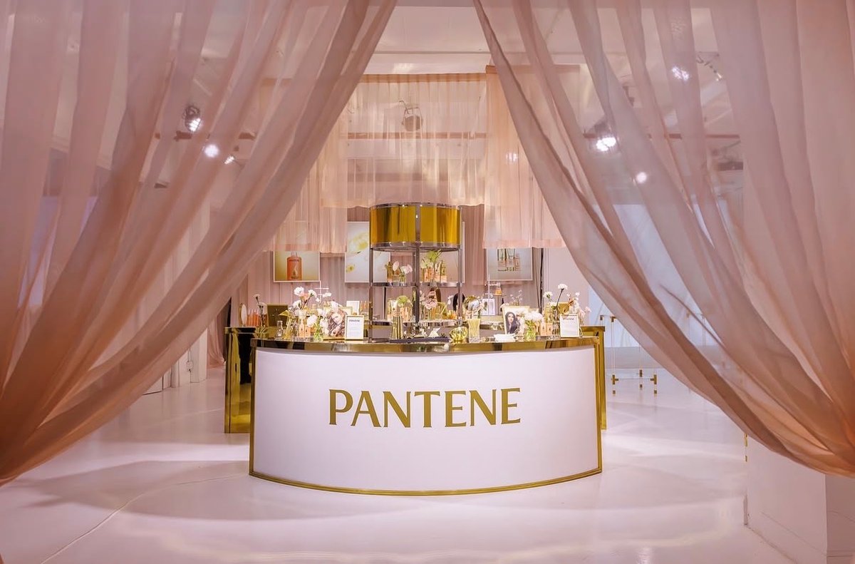 A beautifully arranged product display station for Pantene, featuring a white bar with gold lettering and trim. The stat