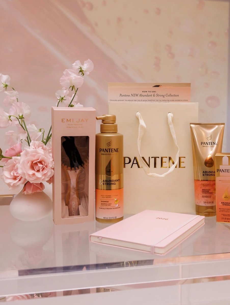 This photo showcases a collection of beauty products, including Pantene shampoo and conditioner, alongside an Emi Jay ha