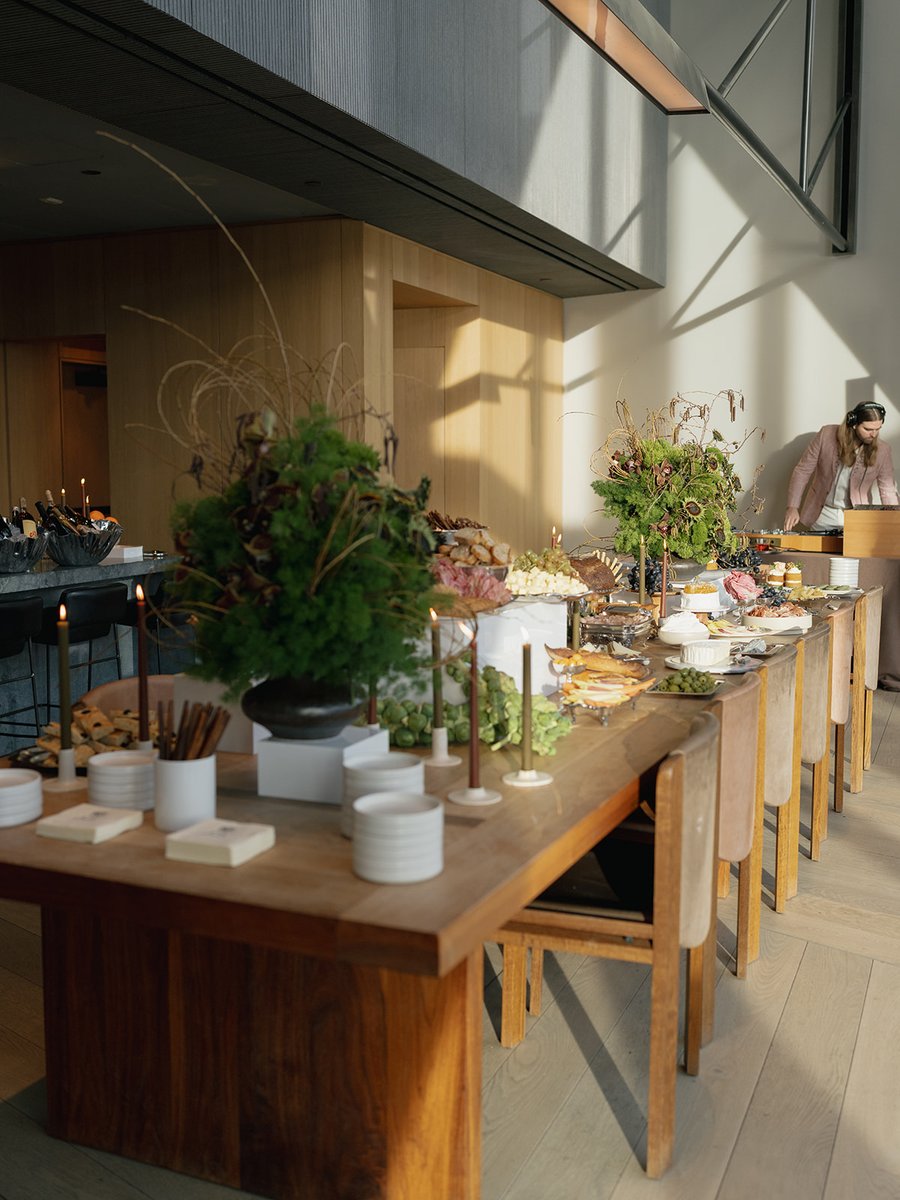 A long, beautifully arranged buffet table laden with various food items and elegant decor takes center stage in a modern