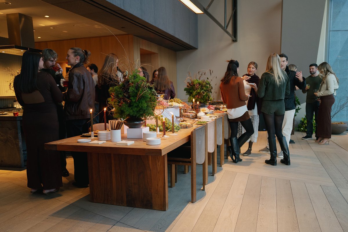 Guests are gathered around a beautifully arranged buffet table, socializing and enjoying food and drinks. The setting ap