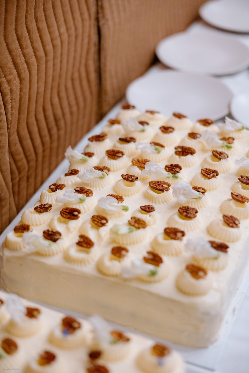 A beautifully arranged rectangular sheet cake or dessert platter is the focal point, adorned with neat rows of piped cre