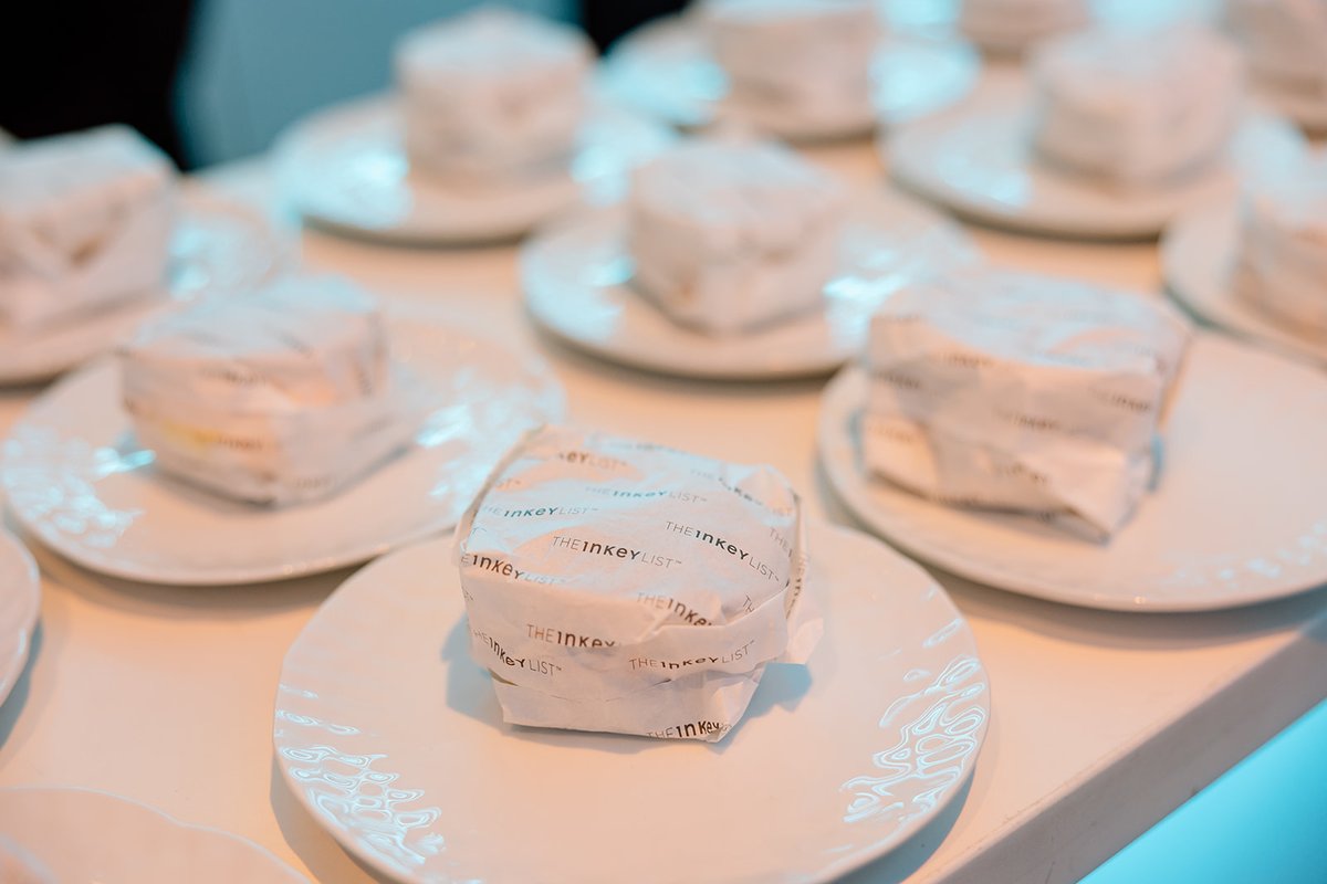 Multiple individual dessert portions, each wrapped in branded paper from 'THE INKEY LIST', are arranged on white plates.