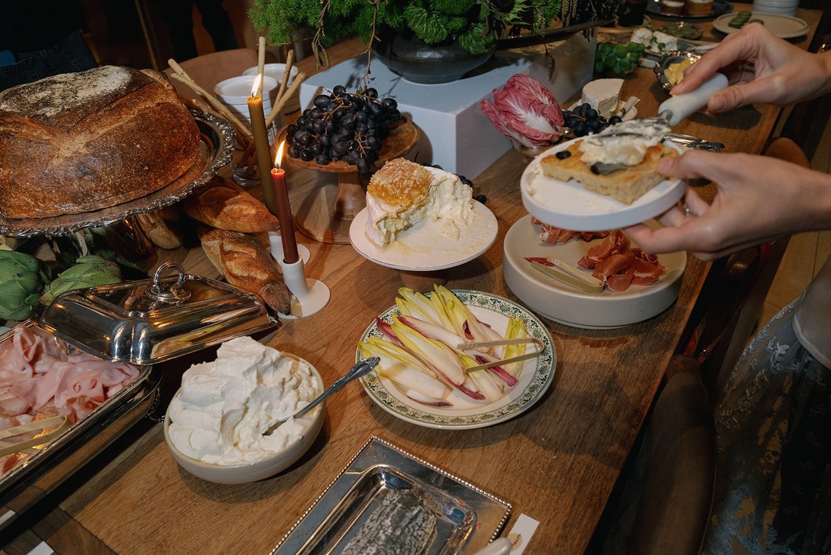 A guest's hands are seen serving themselves from a beautifully arranged buffet table. The table is laden with various ap