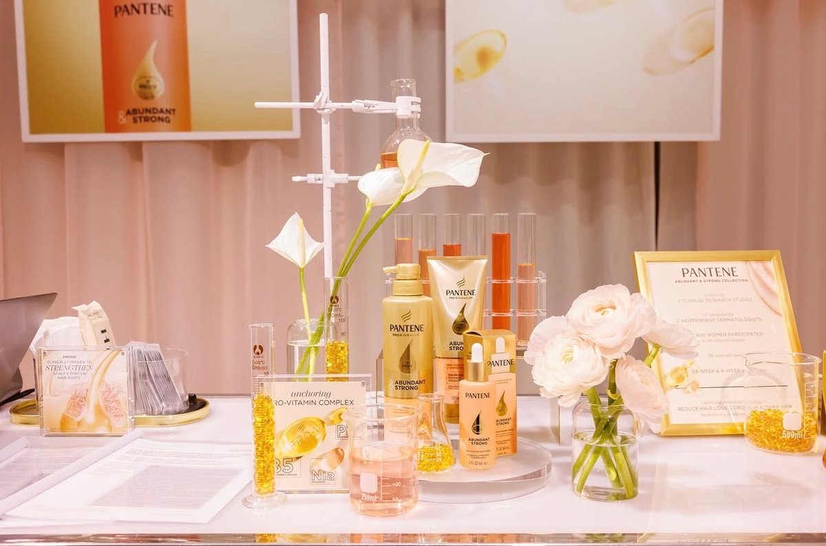 A meticulously arranged display showcases Pantene 'Abundant & Strong' hair products, presented alongside scientific beak
