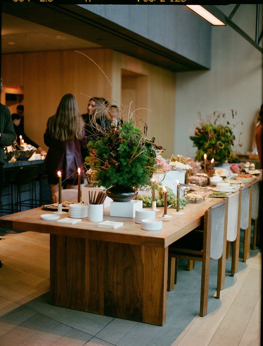 An elegant buffet table is laden with various food items and decorative elements, including lush greenery and lit candle