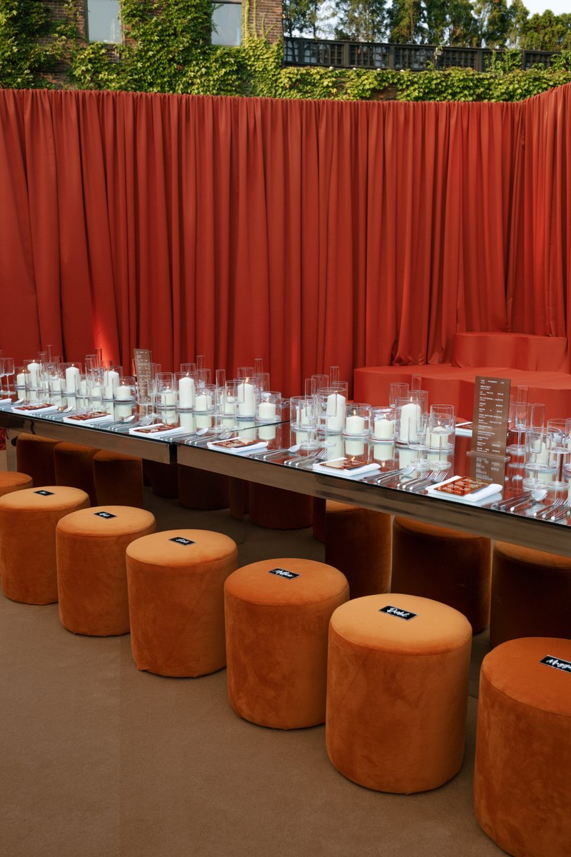 A meticulously arranged dining table, featuring a reflective surface adorned with numerous white candles in glass holder