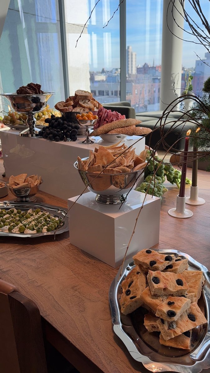 An elegant buffet food display is set up on a long wooden table, featuring various appetizers and breads. The display is