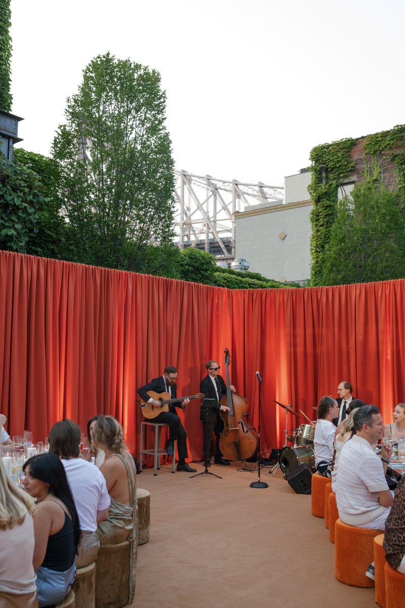 This photo captures an outdoor event with live music, featuring a band with a guitarist, upright bassist, and drummer pe