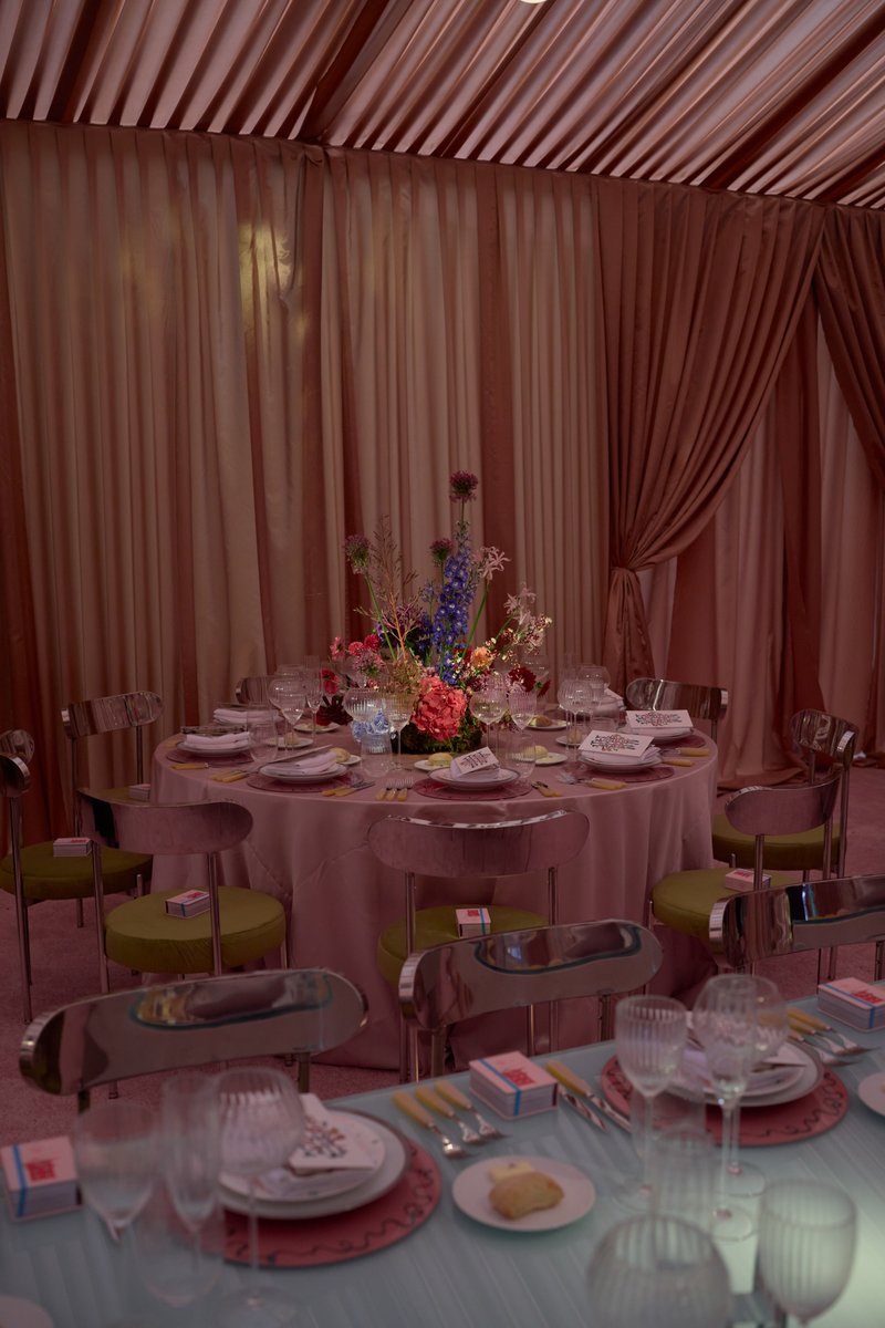A beautifully set round dining table is the focal point, adorned with an elaborate floral centerpiece and surrounded by 