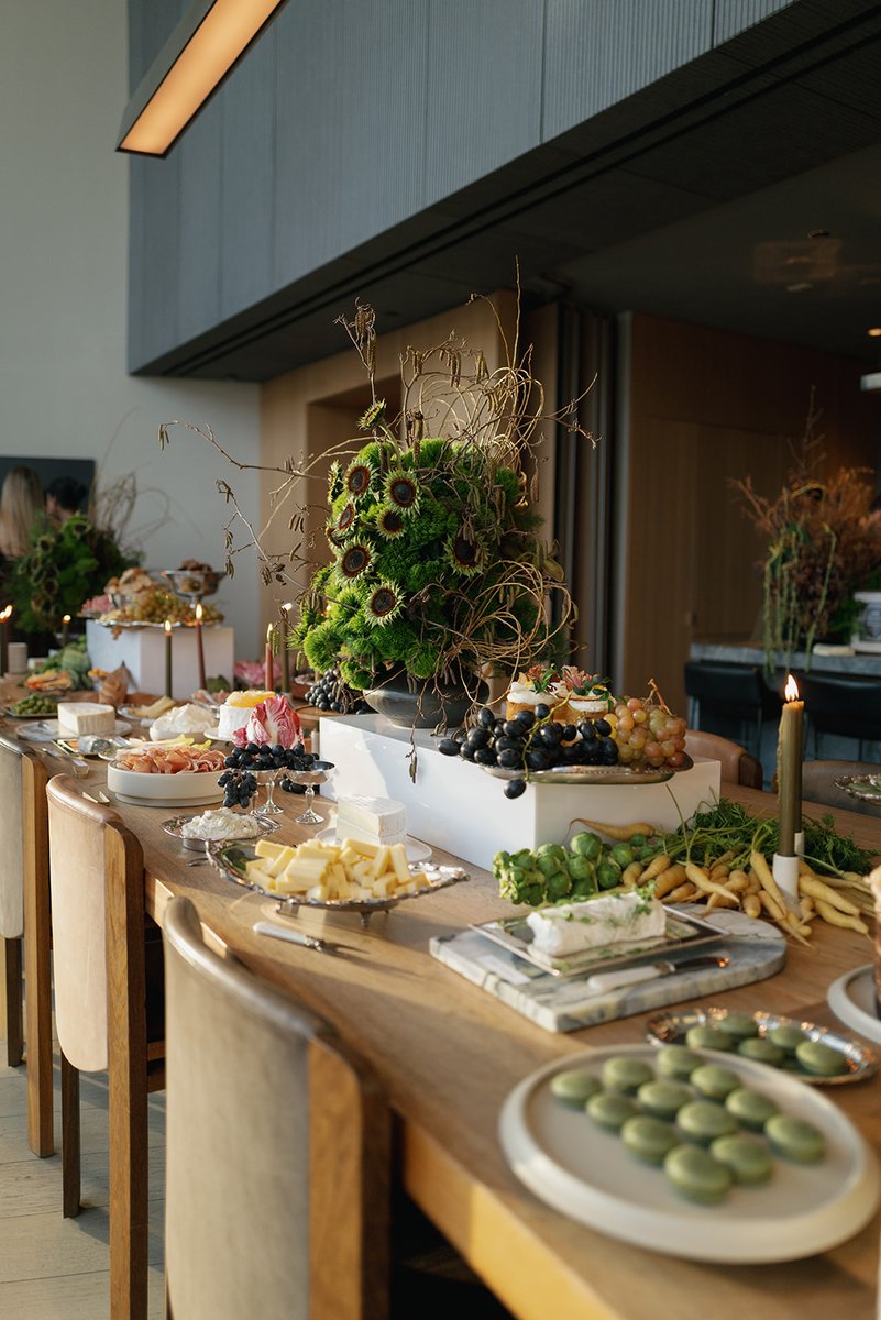 An elegant grazing table is set with an abundant array of cheeses, cured meats, fresh fruits, and vegetables. Decorative