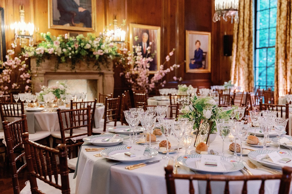 This photo captures a beautifully set dining room, likely for a formal event, with multiple round tables adorned with el