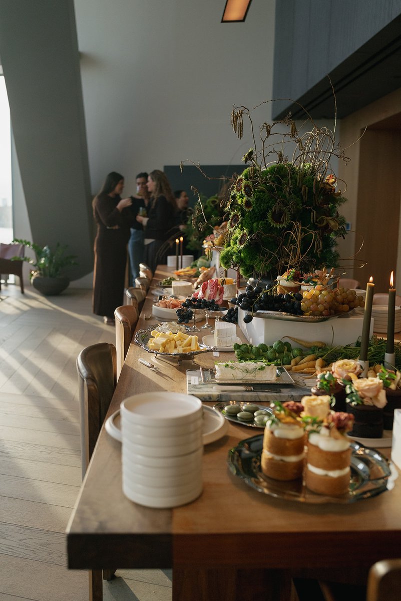 A beautifully arranged buffet table laden with various gourmet foods takes center stage. In the background, guests mingl
