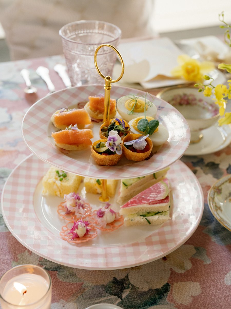 A two-tiered stand filled with an assortment of delicate appetizers and desserts, including mini quiches, smoked salmon 