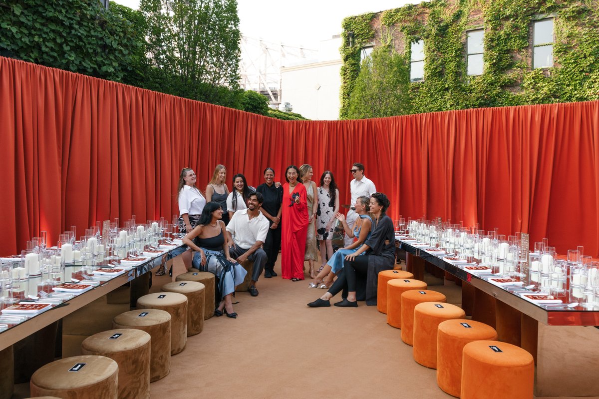 A diverse group of event staff or organizers poses together in a stylish outdoor event space. They are gathered in front
