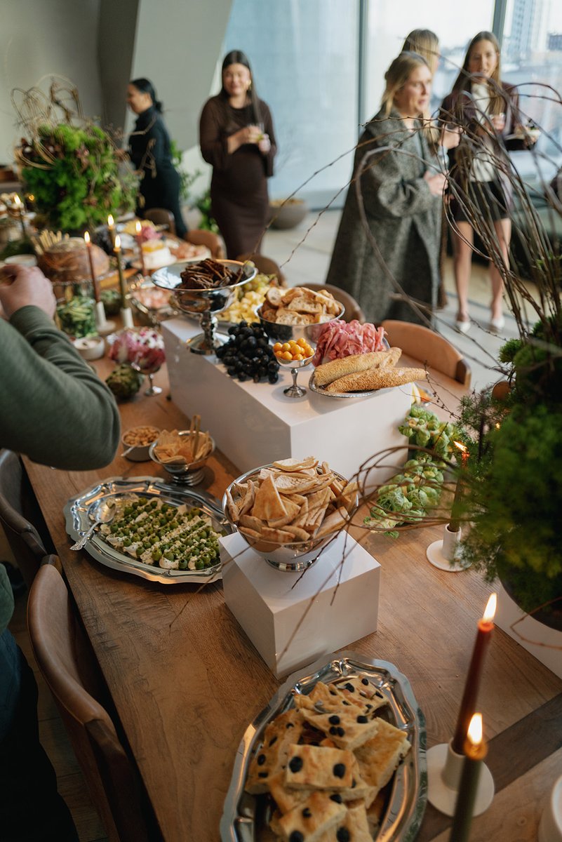 A beautifully arranged buffet table laden with various appetizers and snacks is the focal point of an event. Guests are 