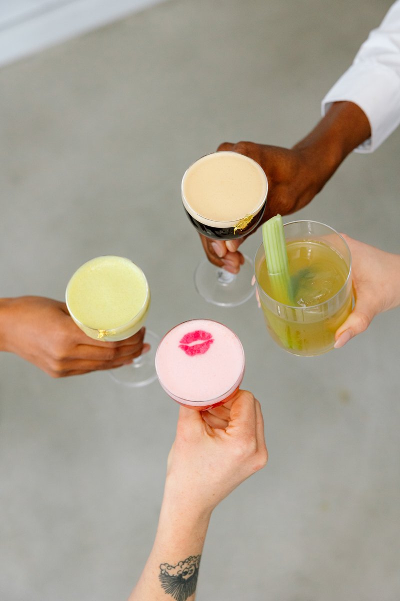 A refreshing close-up of a cocktail in a modern stemmed glass, featuring a large ice cube and delicate green garnish. Th