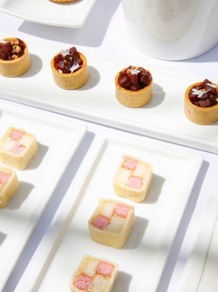 This close-up shot features two types of meticulously arranged desserts on white rectangular plates. In the foreground a