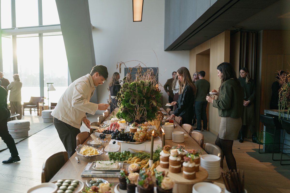 Guests are seen serving themselves from a beautifully arranged buffet table laden with various appetizers and desserts. 