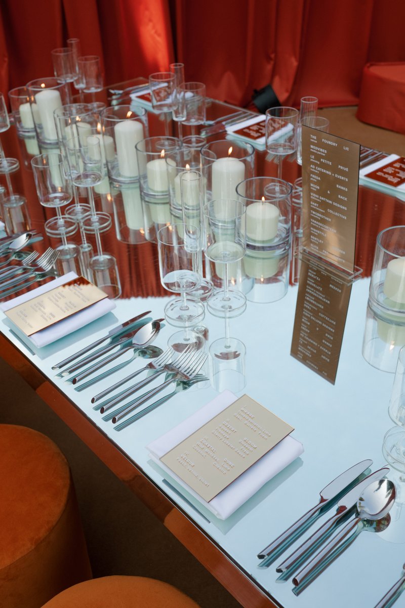 A beautifully set table features an array of lit candles in glass holders, sparkling glassware, and polished cutlery, al