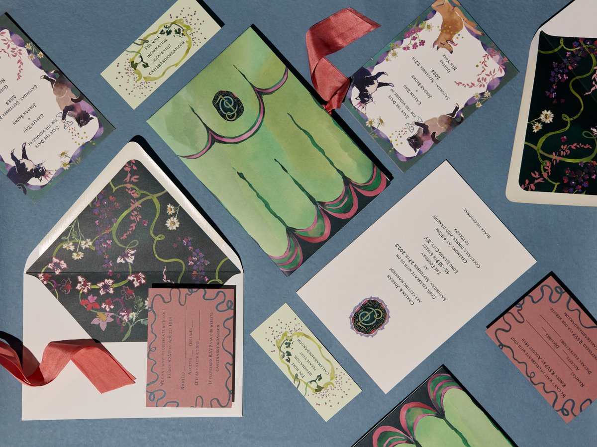 This overhead shot displays a beautifully designed wedding invitation suite, featuring multiple cards, envelopes with pa