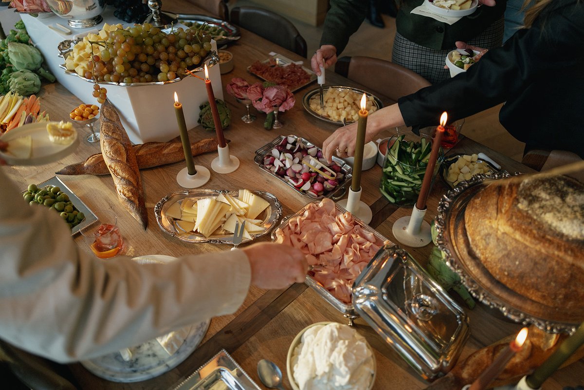 An overhead shot captures guests serving themselves from a lavish buffet table laden with various appetizers. The spread