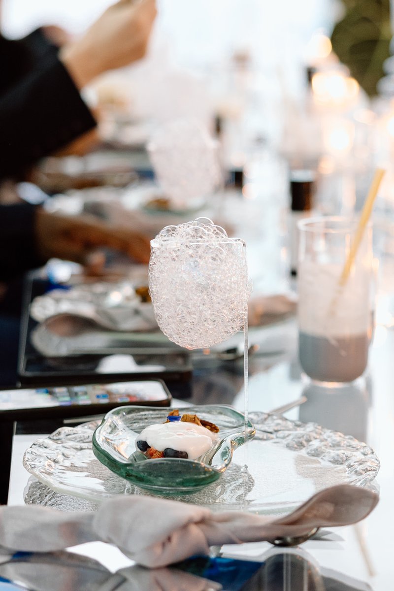 A close-up shot of a modern dessert featuring a unique bubble garnish, served on a clear glass plate. The dessert, toppe