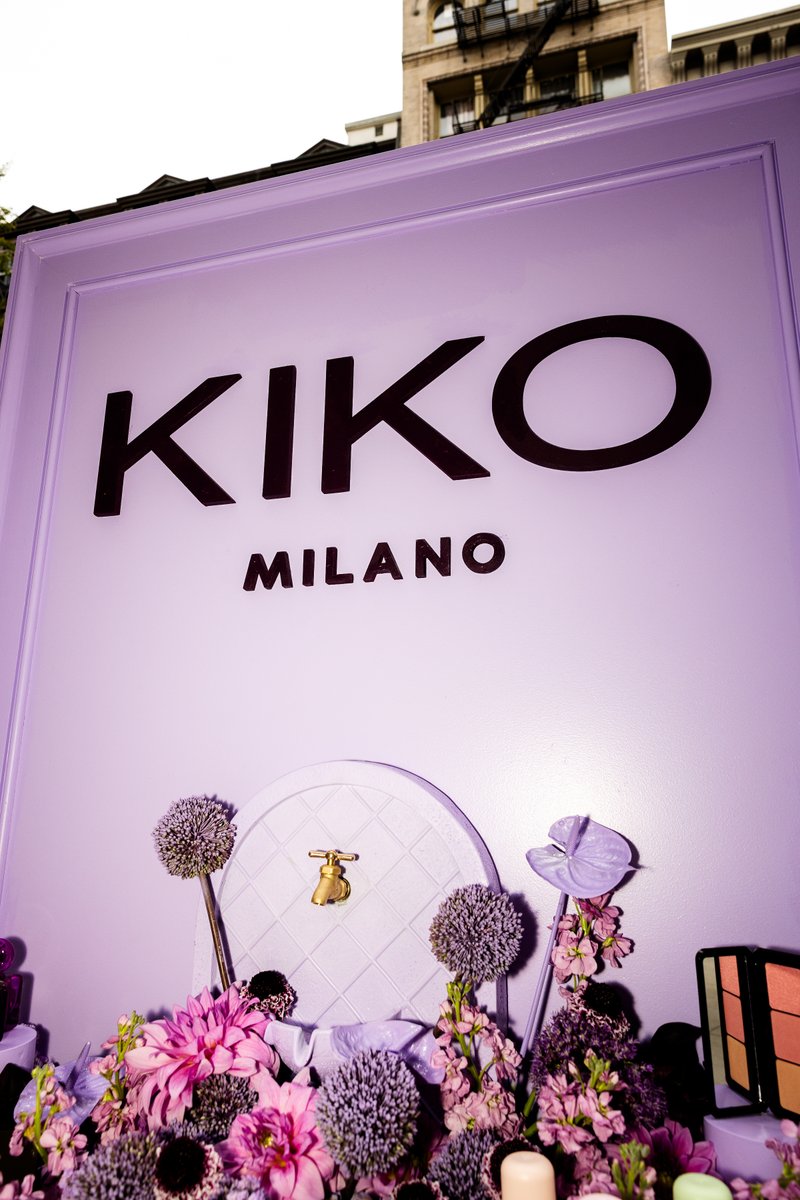 A vibrant KIKO Milano branded display features a large sign with the company logo, surrounded by an abundance of purple 