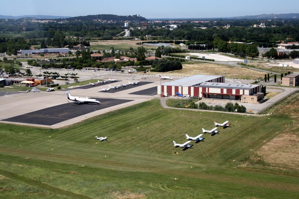 Vue aérienne de l'aérodrome d'Avignon-Caumont : parking herbe, hangar et tarmac.