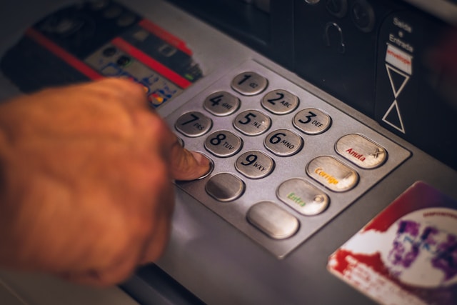 Hand pressing a button on an ATM machine. Photo by Eduardo Soares.