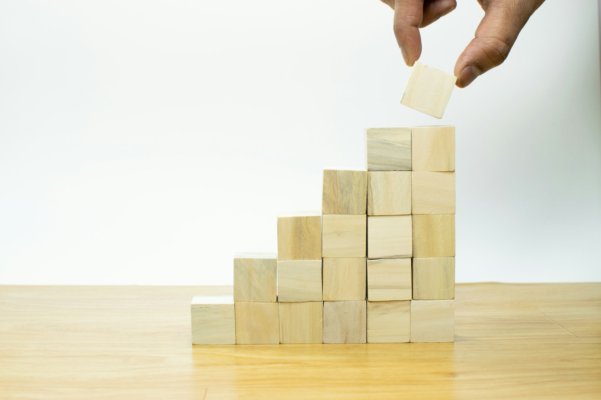 Businessman hand putting blank wooden cube block stack on white background with copy space for input text, icon, trend, creative idea, finance, leadership, strategy, business, online marketing concept. Photo by Imagine Buddy on Unsplash