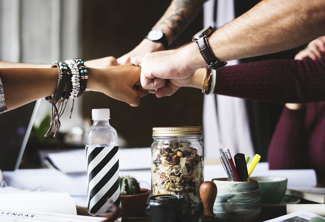A group of people with knuckles together, symbolizing teamwork and collaboration.