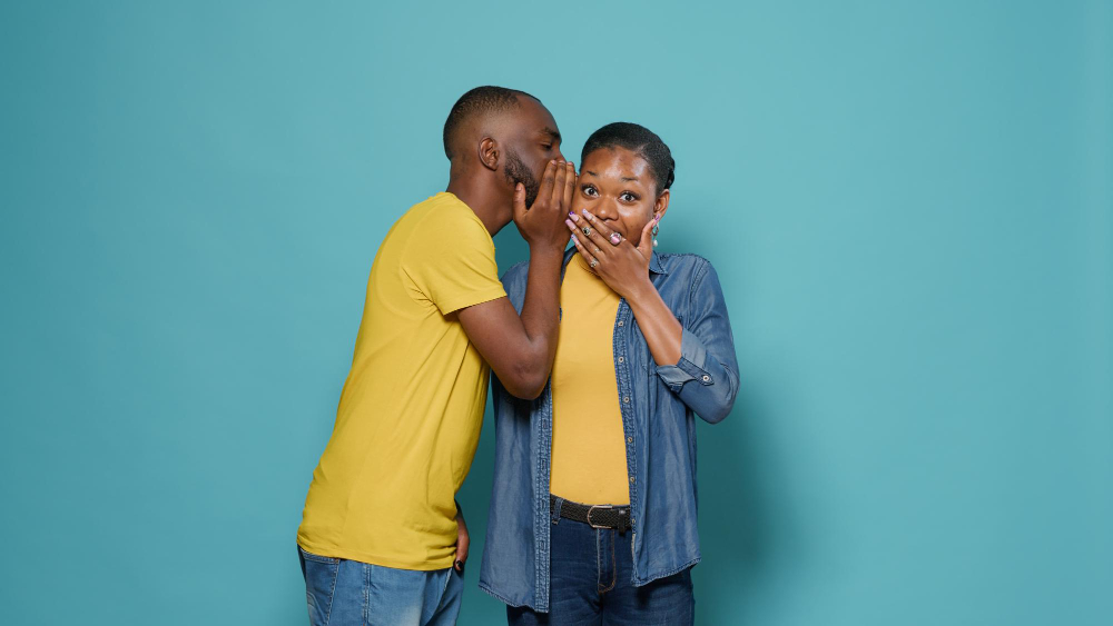 Man whispering into the ears of a woman. Photo by DC Studio.