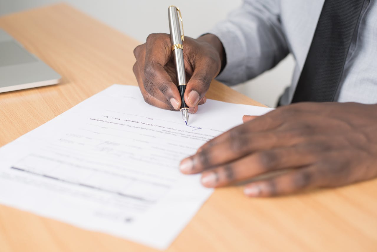 A man signing a document with a pen. Photo by Cytonn Photography on pexels.com