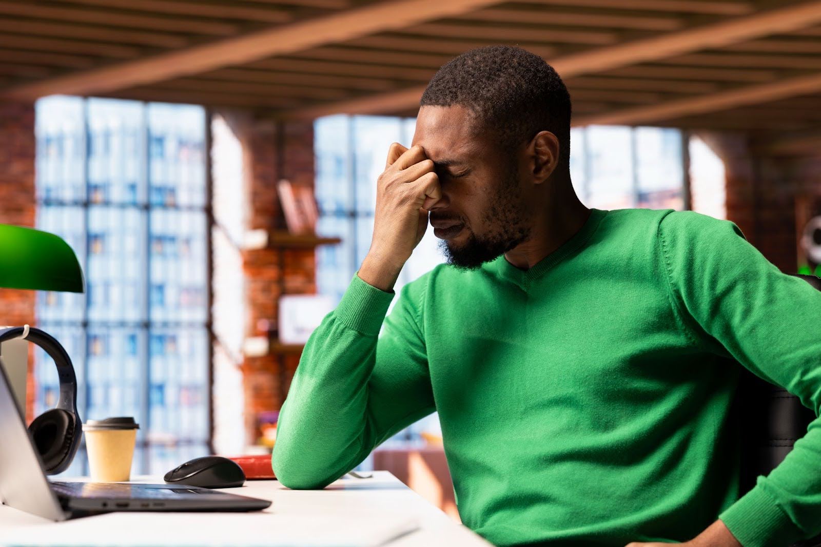 Picture of a man that looks stressed out, sitting at a desk with his head in his hands.