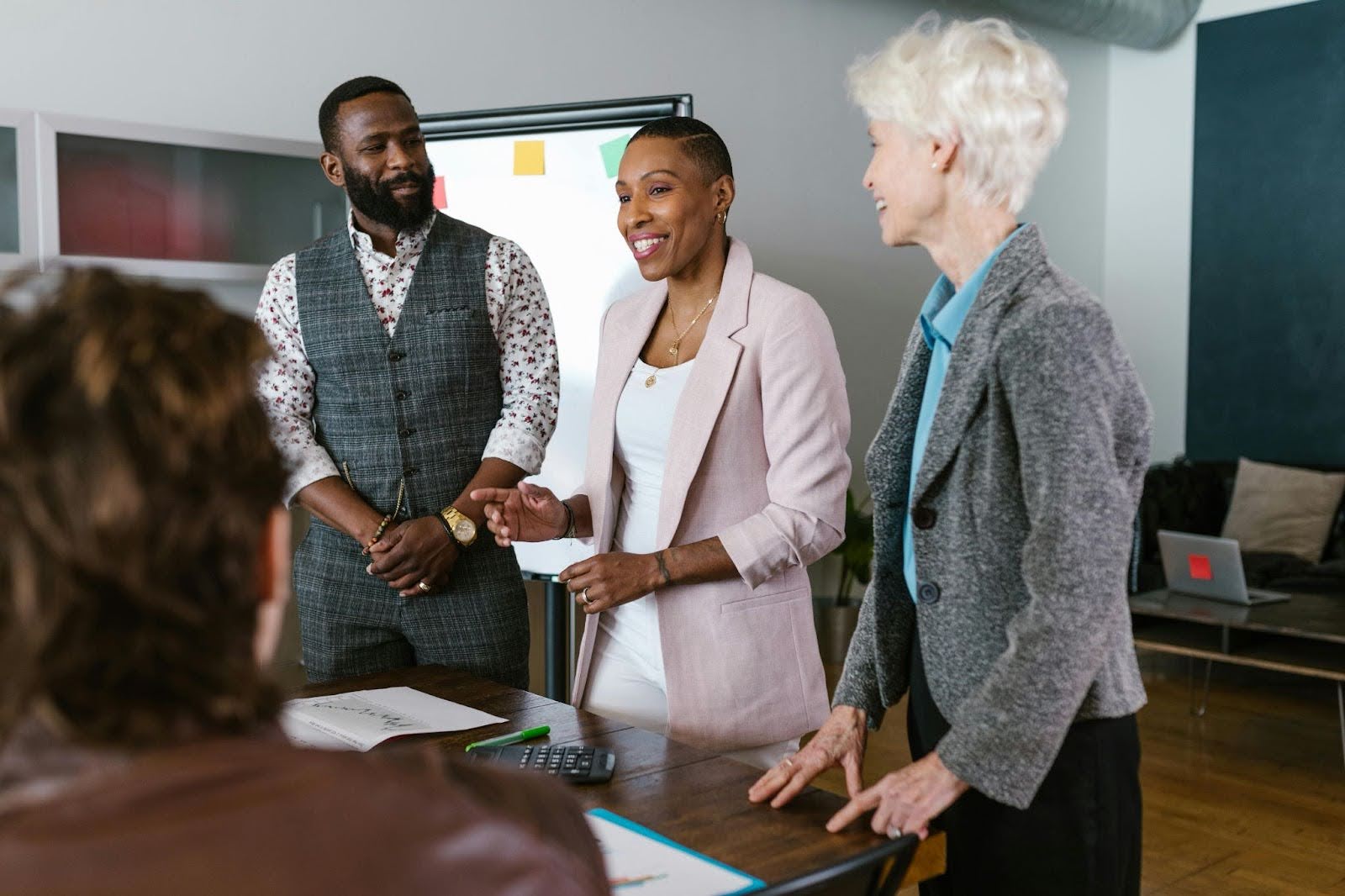 Three people standing in front of a group while making a presentation