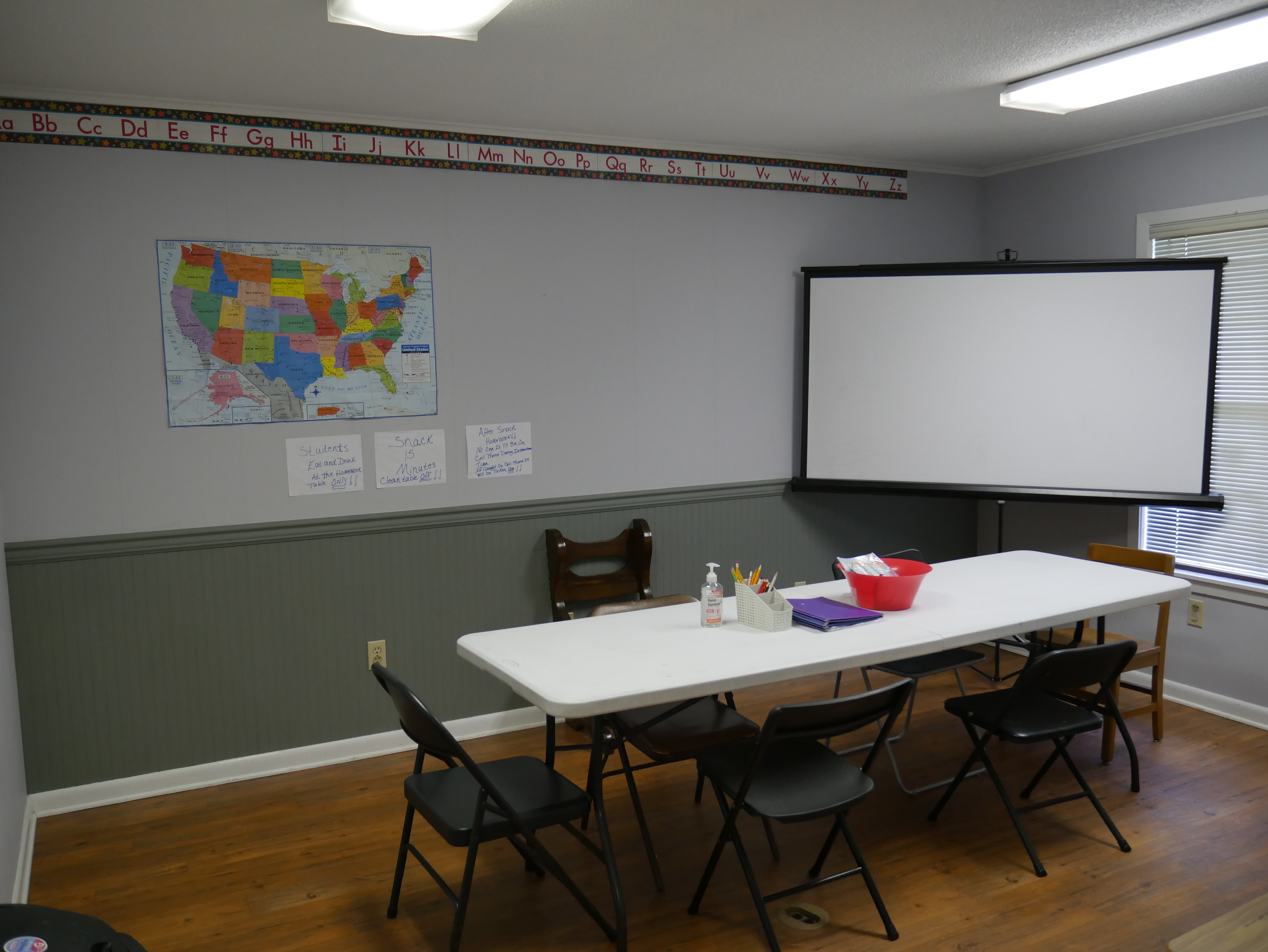 Group learning room with tables, chairs, a map, and projector screen