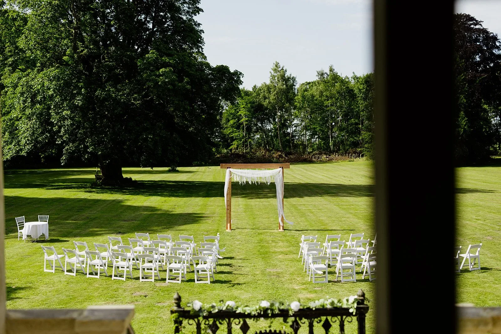 Udendørs vielse med hvide stole og bue på plænen foran Agerup Gods