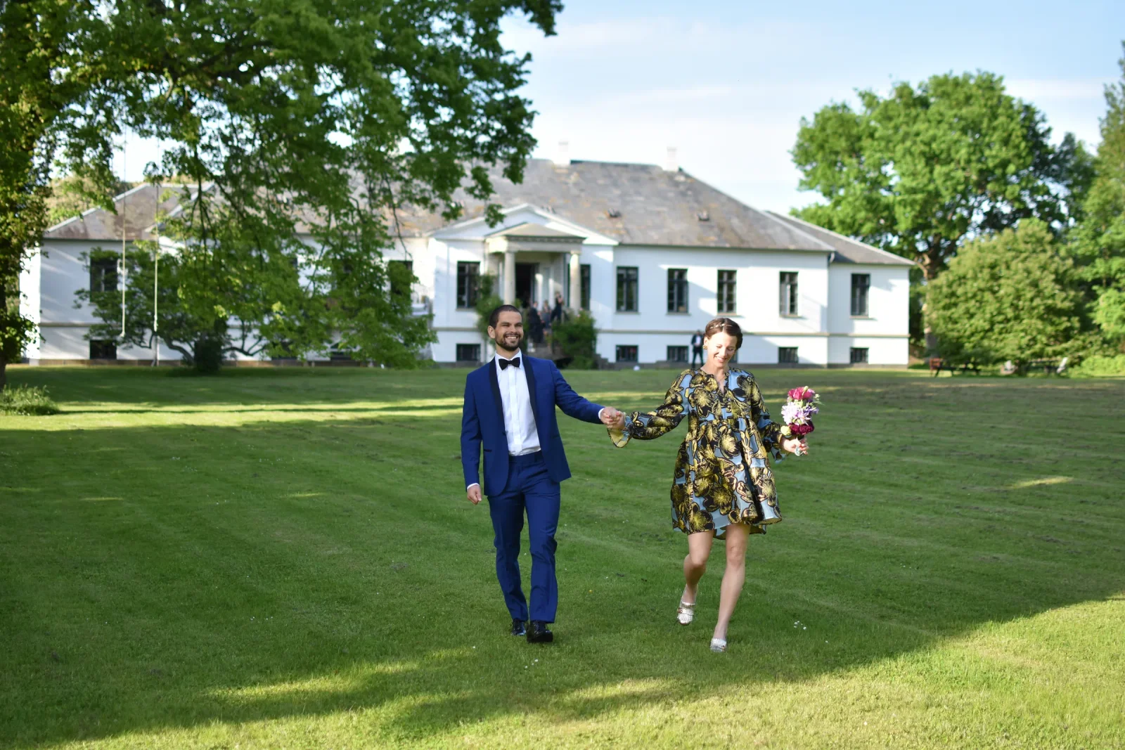 Brudepar går over plænen foran herregården på Agerup Gods en sommerdag