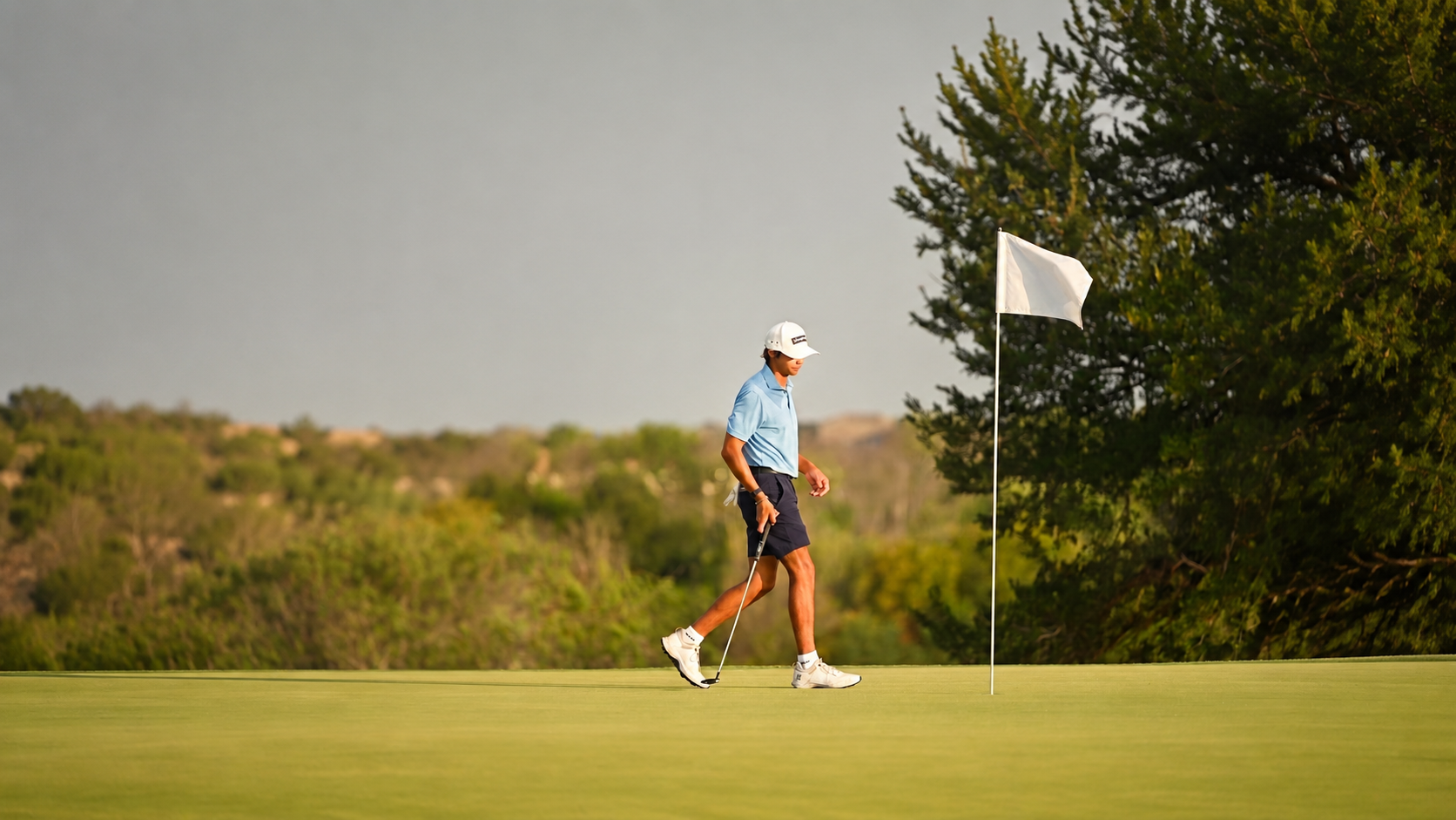Golfer walking on the putting green near the flag