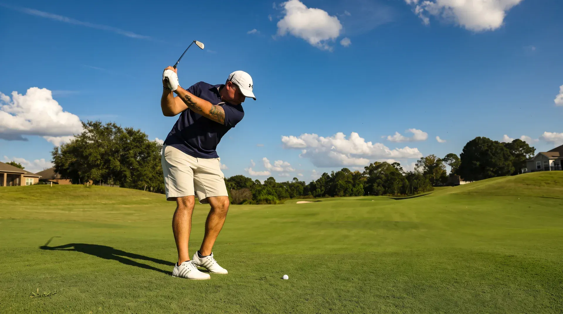 Golfer swinging an iron on a sunny fairway.