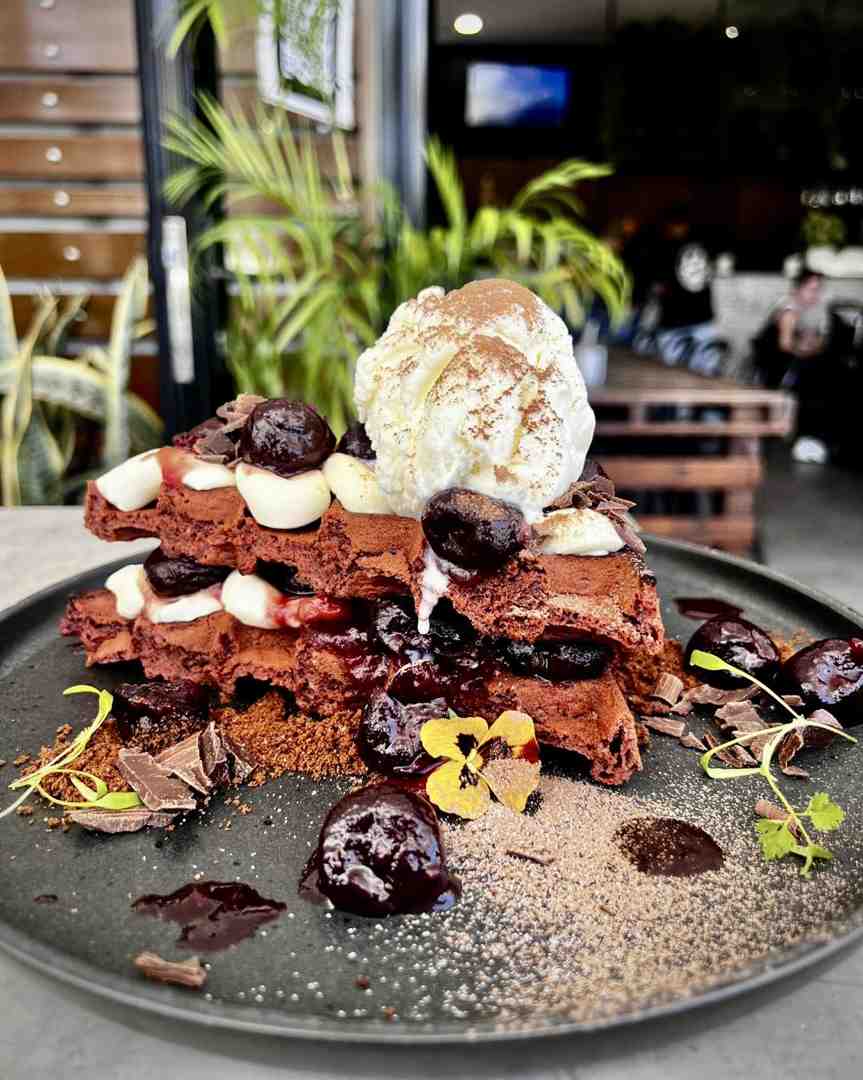 Decadent black velvet waffles layered with dark cherry compote, cream, and vanilla ice cream, making an outstanding choice over simple pancakes or waffles.