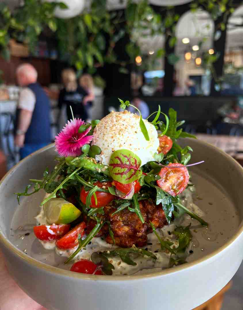 House-made corn fritters served with poached egg, avocado, tomato salad, dukkah, and rocket.