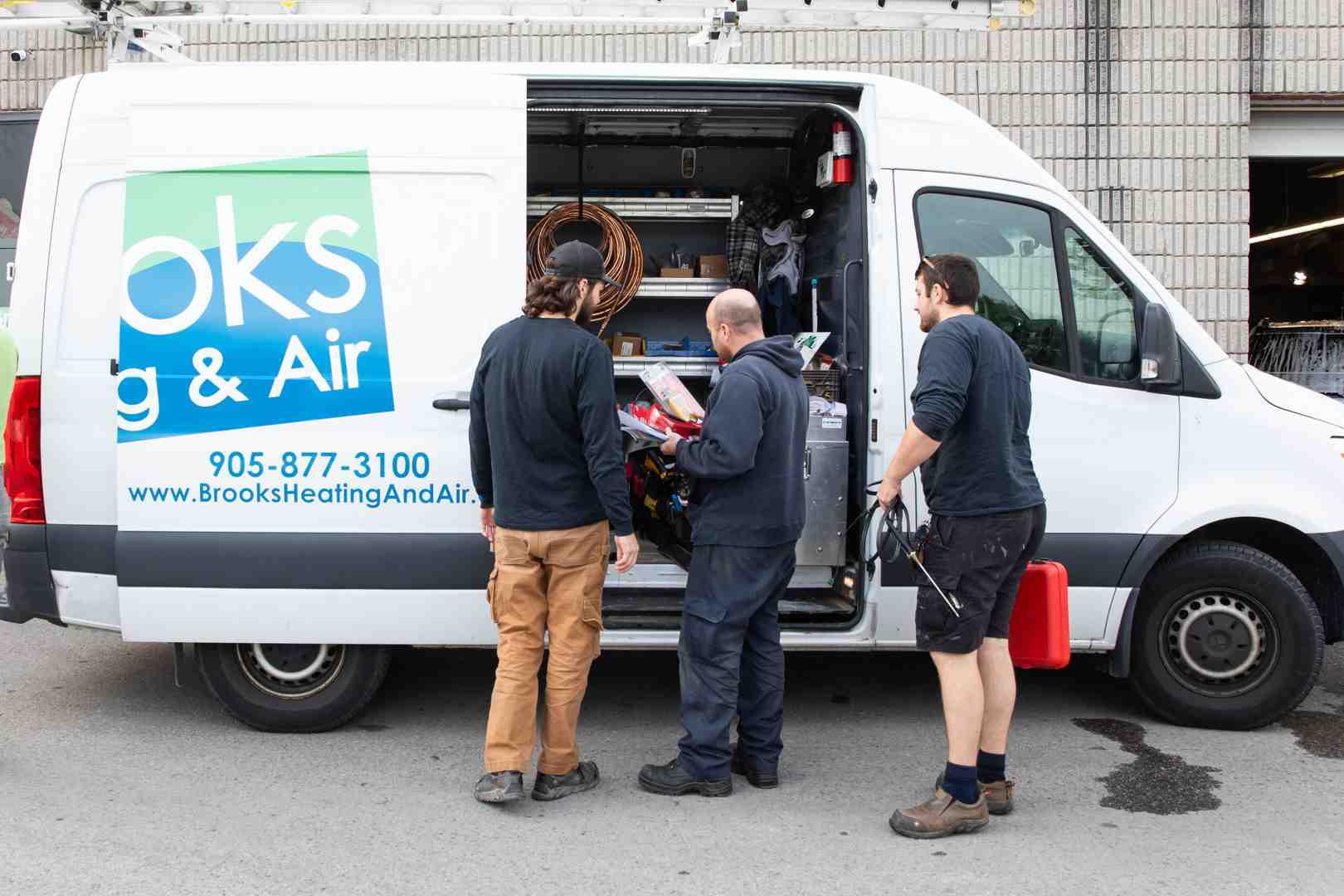 Image of a professional team loading an old AC unit onto their service truck - Milton air conditioner