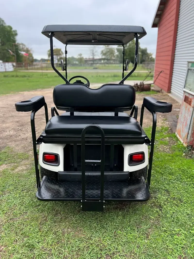 A Yamaha golf cart rear seat kit flipped down into cargo bed mode in a suburban driveway