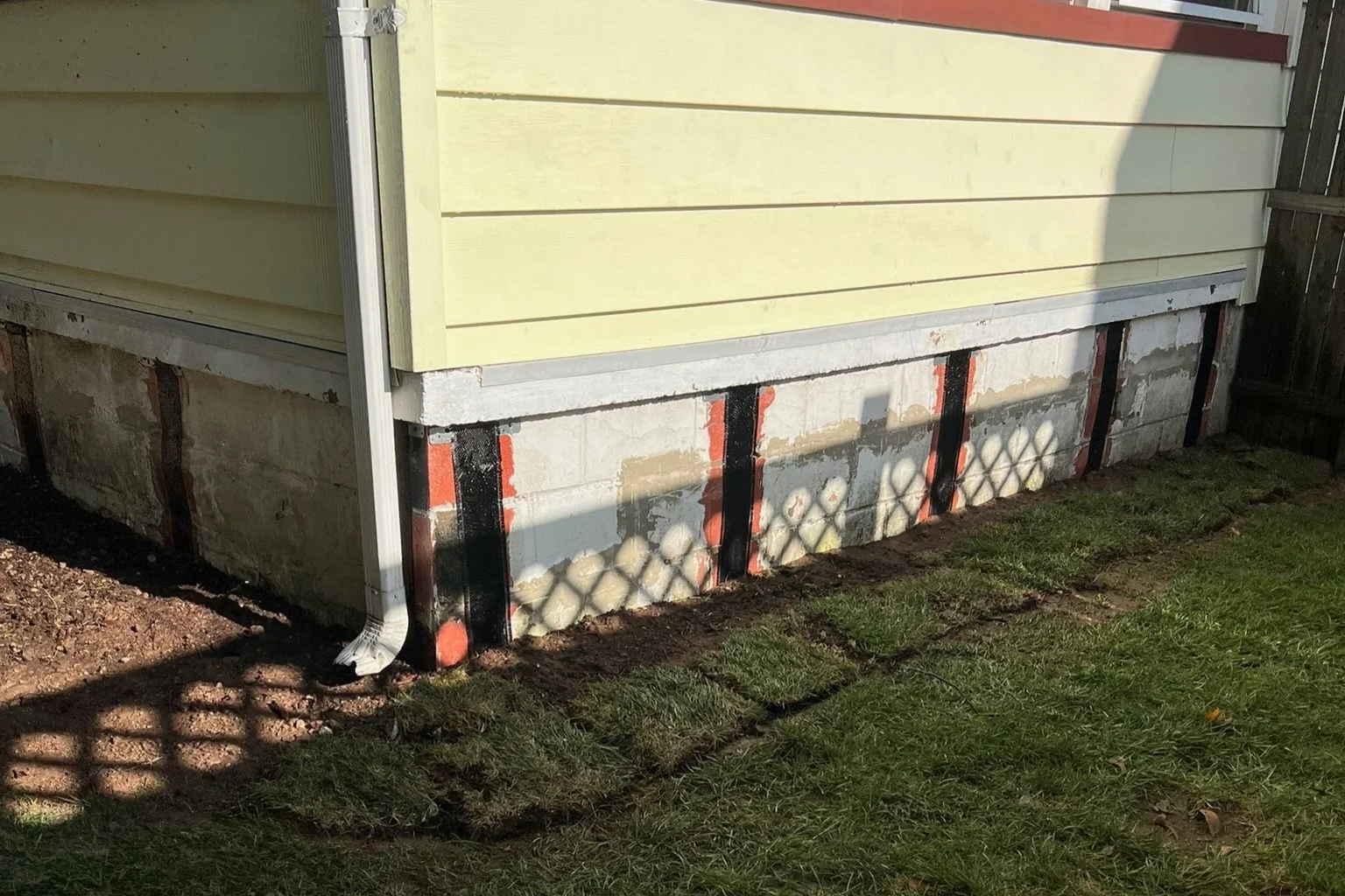 Exterior view of a foundation wall with horizontal cracks, indicating potential structural issues.