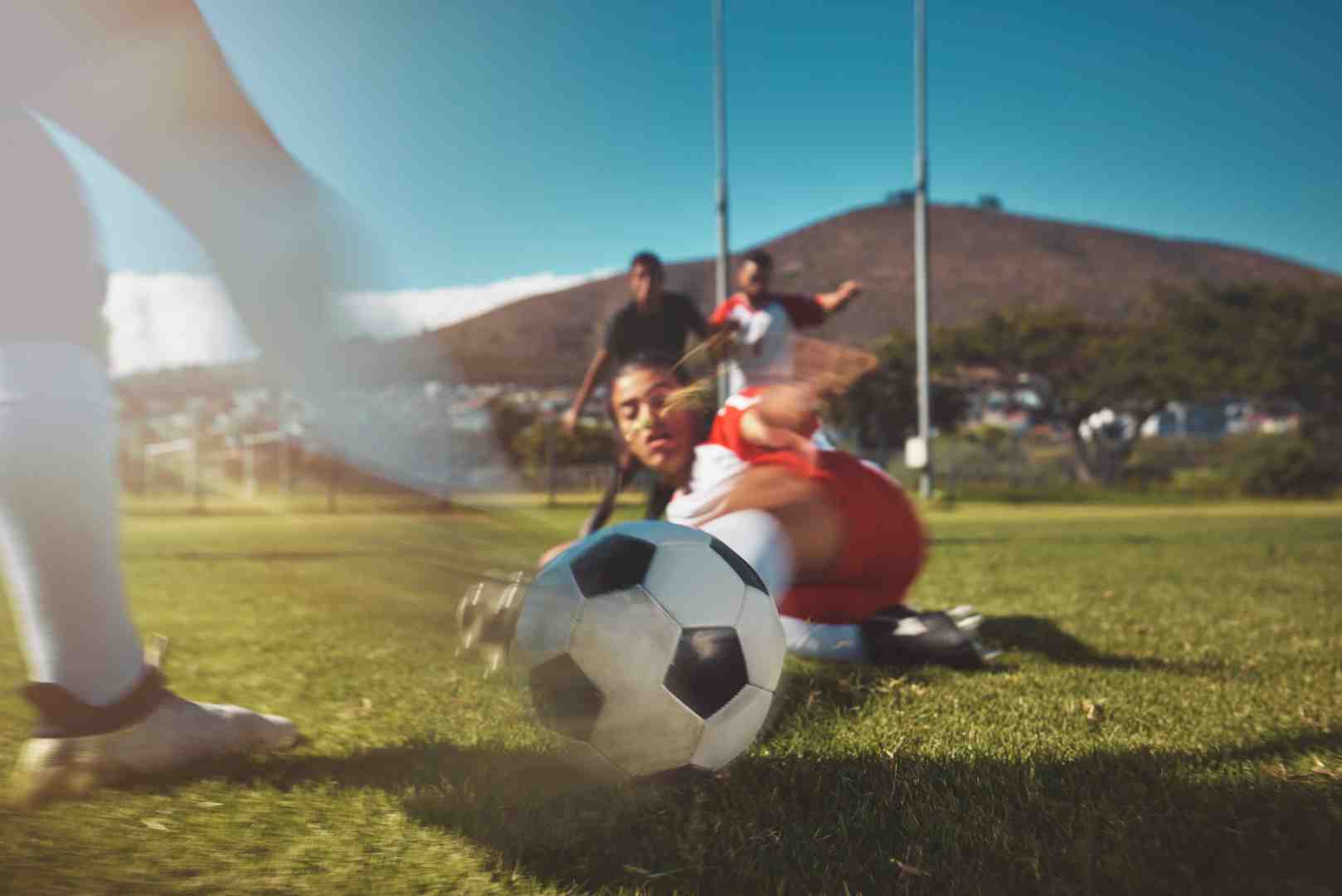 female athletes - a soccer pitch scene shows a female athlete diving for the ball.